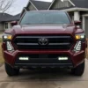 Front view of red 2024 Toyota Tacoma with both white LED fang lights illuminated below the headlights