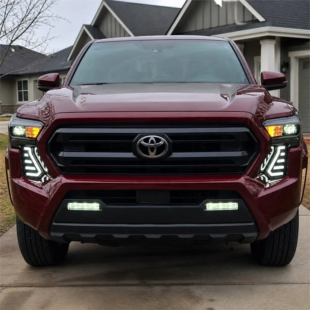 Front view of red 2024 Toyota Tacoma with both white LED fang lights illuminated below the headlights