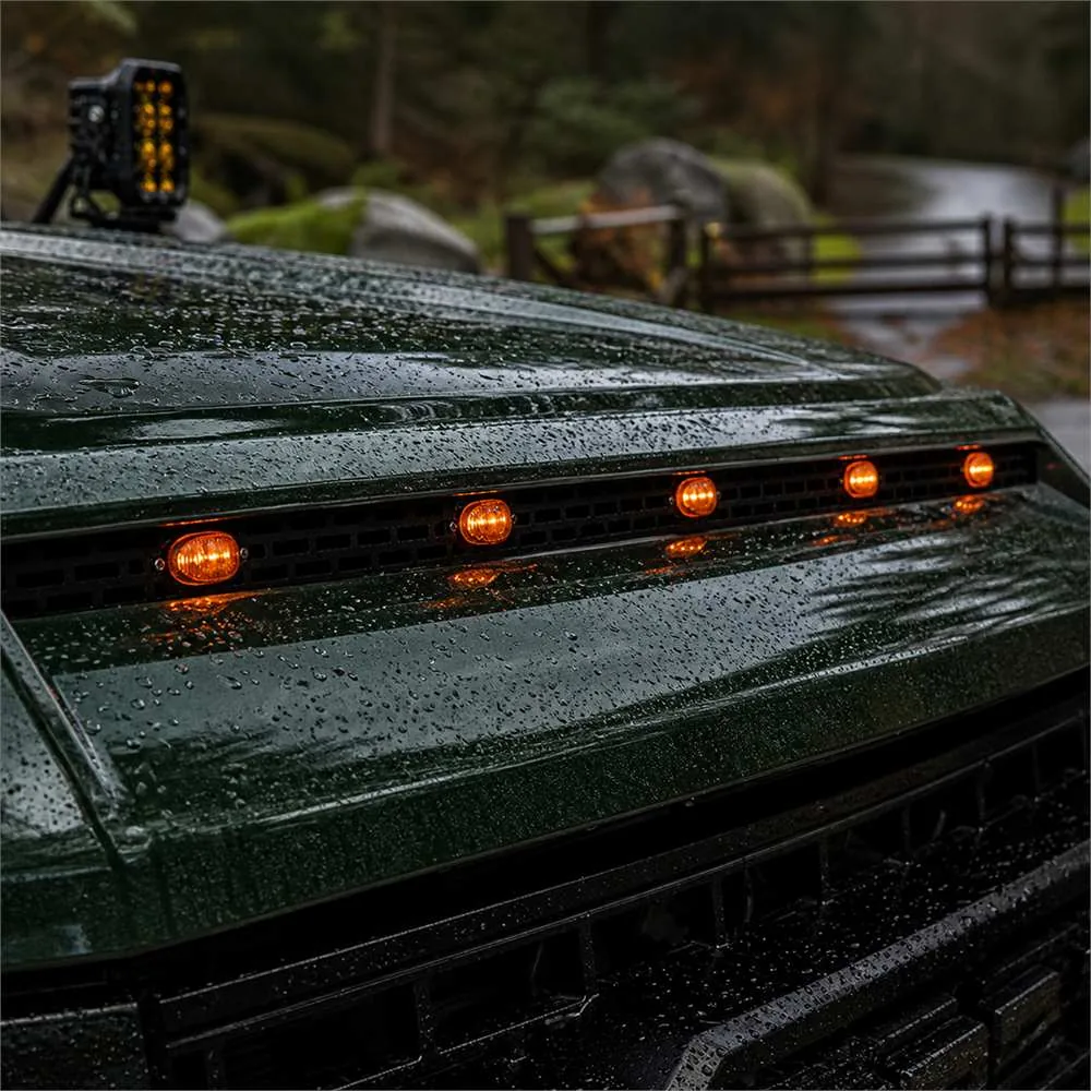 Five amber marker lights reflected on the wet hood of a dark green truck
