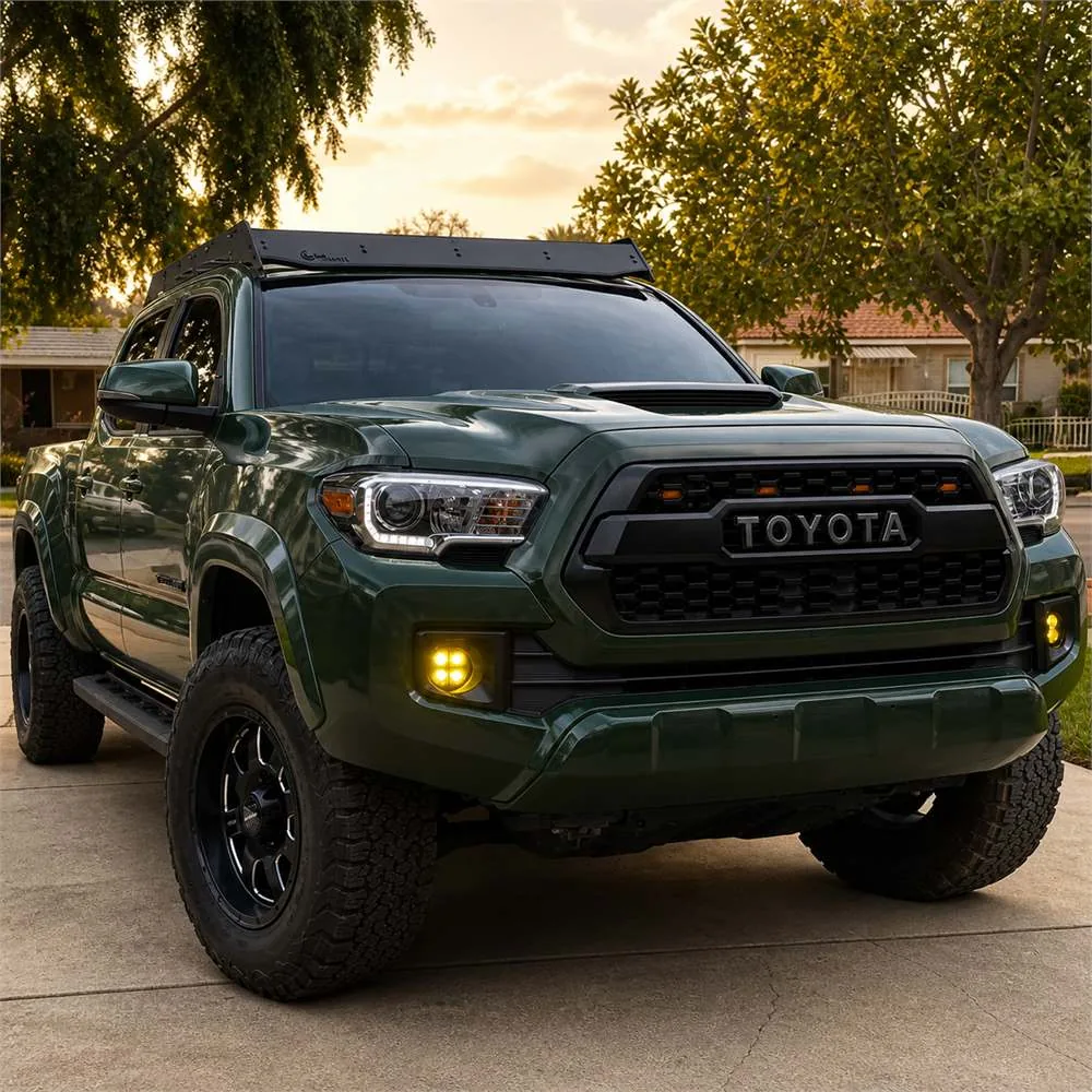 Green third-generation Toyota Tacoma on a driveway with four-module yellow LED fog lights installed in the factory bumper openings