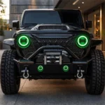 Front view of a black modified Wrangler with synchronized green halos glowing in the headlights and bumper fog lights