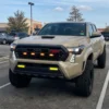 Lifted Toyota Tacoma TRD front view with white fang light DRLs illuminated in a parking area