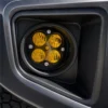 Close-up of one round four-module yellow fog light installed inside the black factory-style Tacoma bumper bezel