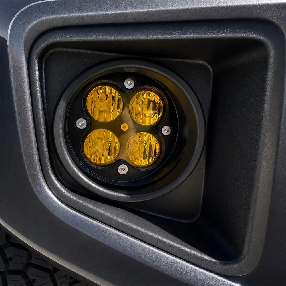 Close-up of one round four-module yellow fog light installed inside the black factory-style Tacoma bumper bezel
