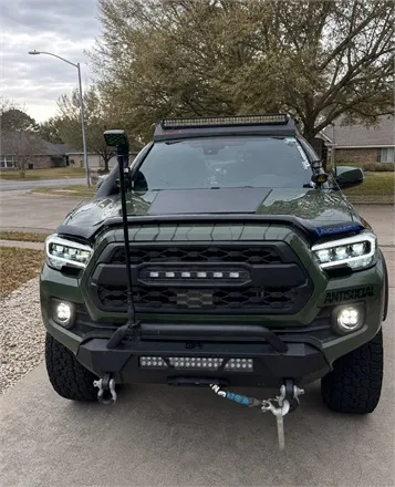 Real buyer review photo of a green Toyota Tacoma with off-road LED lights in a suburban driveway