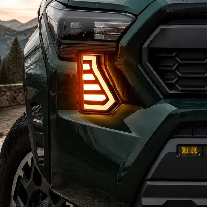 Close-up of amber Tacoma fang light installed below the headlight on a green 2024 Toyota Tacoma outdoors
