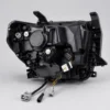 Rear view of a Tundra headlight housing showing mounting tabs bulb access covers adjusters and wiring connectors