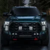 Front view of a modified Toyota Tundra in a forest with five white DRL bars illuminated in each vertical vent panel