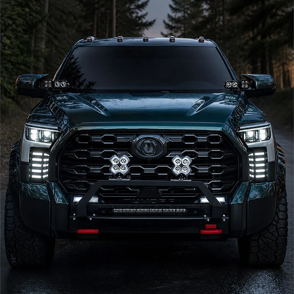 Front view of a modified Toyota Tundra in a forest with five white DRL bars illuminated in each vertical vent panel