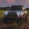 5th gen Toyota 4Runner with aftermarket headlights installed on an off-road build at sunset.