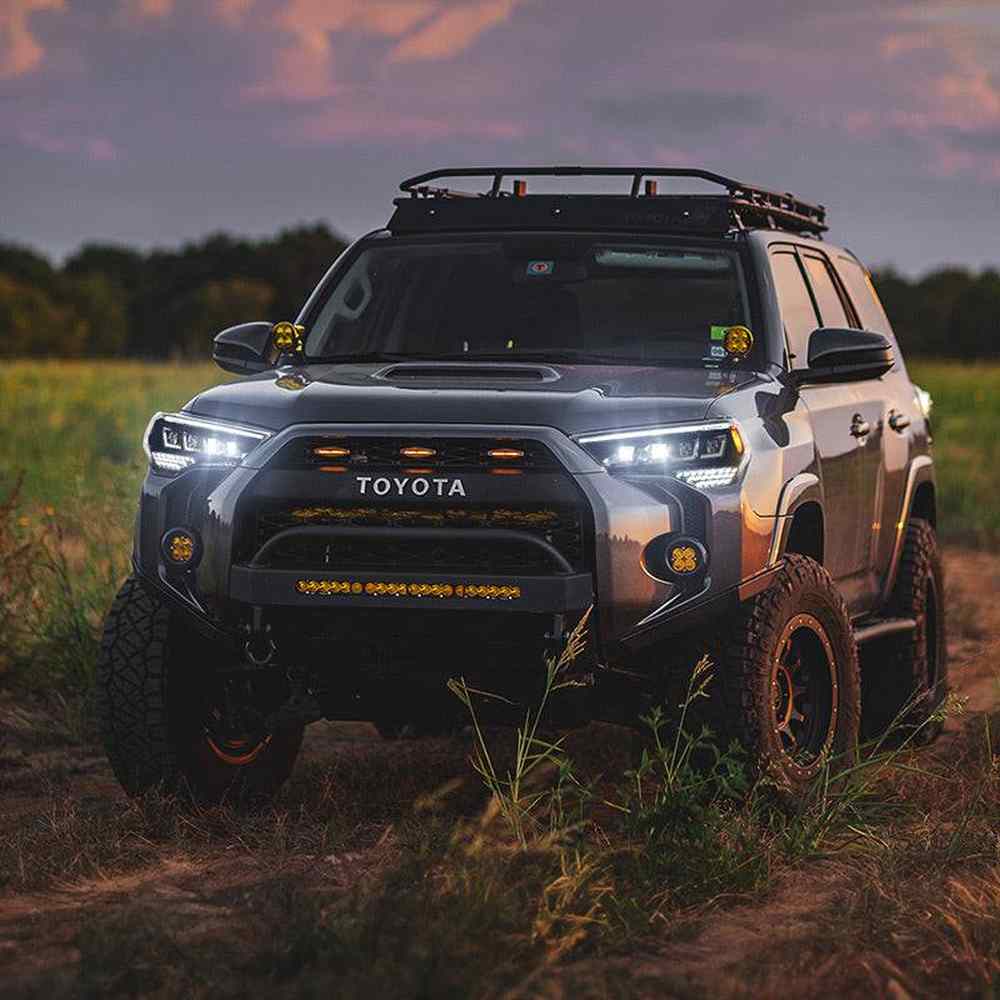 5th gen Toyota 4Runner with aftermarket headlights installed on an off-road build at sunset.