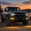 Ford Bronco with triple amber auxiliary lamps illuminated on a sunset trail