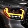 Toyota Tundra headlights showing amber sequential turn signal lighting around triple projector lenses